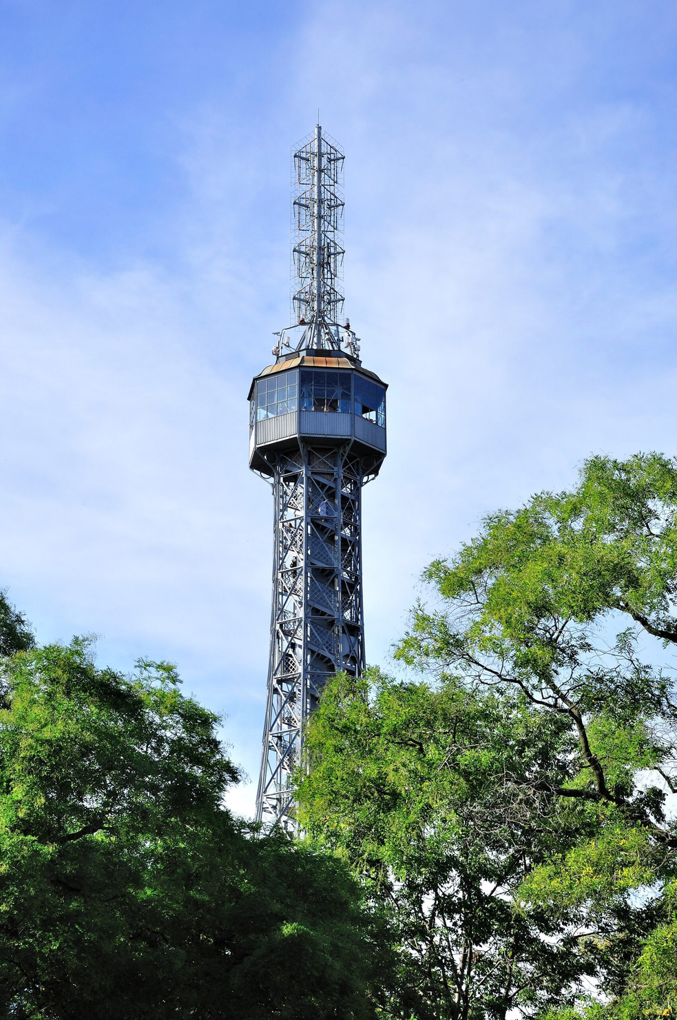 Metal tower on the top of  the Petrin hill in Prague (Czech Republic) which name is Petrin tower behind the tree.